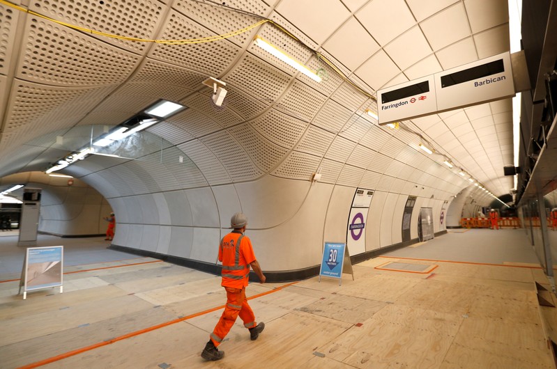 A Crossrail worker walks in the new Farringdon underground station of the Elizabeth line which opens in December 2018, in London