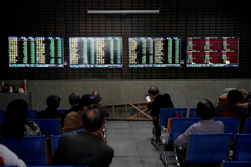 Investors look at screens showing stock information at a brokerage house in Shanghai