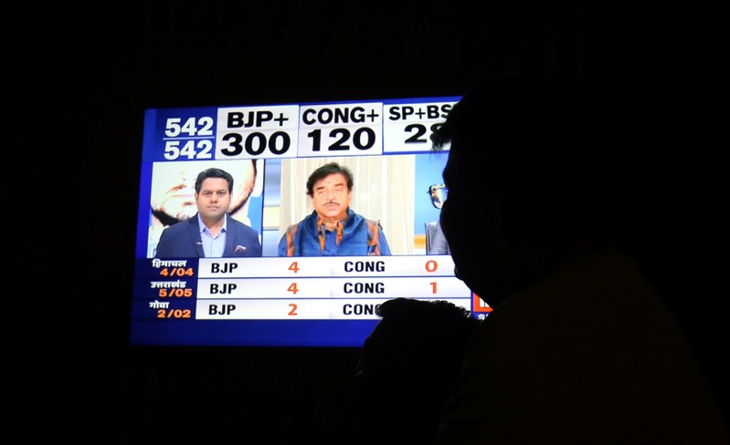 A man looks at a television screen showing exit poll results after the last phase of the general election in Ahmedabad