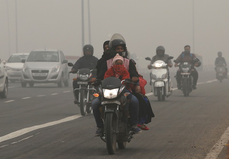 FILE PHOTO: People commute on a smoggy morning in New Delhi
