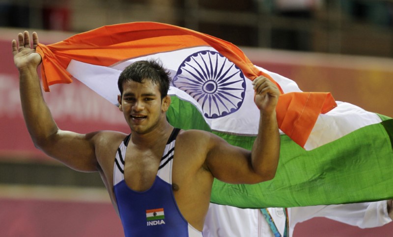 India's Yadav holds his national flag as he celebrates winning the gold medal in the 74kg men's freestyle wrestling match at the Commonwealth Games in New Delhi