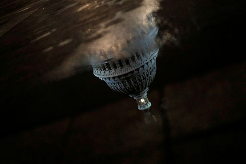 FILE PHOTO: A reflection of the U.S. Capitol Building as seen ahead of a vote on the coronavirus (COVID-19) relief bill on Capitol Hill in Washington