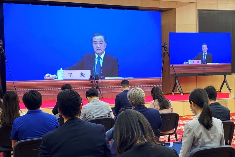 Chinese State Councillor and Foreign Minister Wang Yi is seen on screens during a news conference held via video link in Beijing