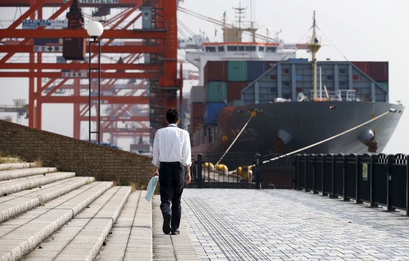 A man walks near a container ship at a port in Tokyo